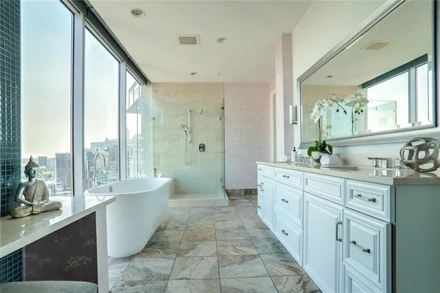 a spacious bathroom with a double vanity sink a large mirror and a bathtub