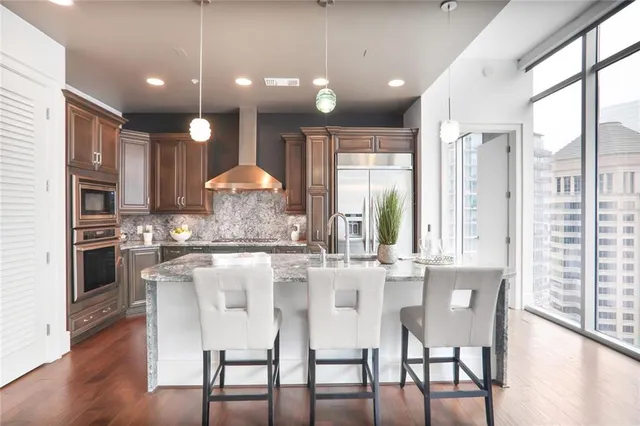 a kitchen with stainless steel appliances granite countertop a stove a refrigerator and a dining table with wooden floors