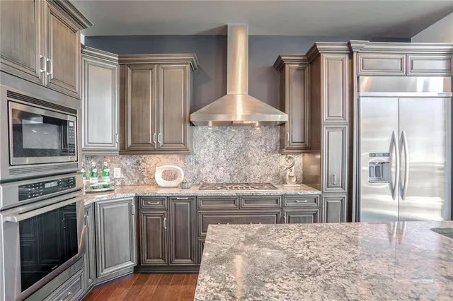 a kitchen with stainless steel appliances granite countertop a refrigerator and a stove top oven