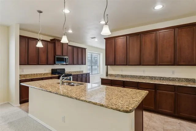 a kitchen with stainless steel appliances granite countertop a sink a oven a counter space and cabinets