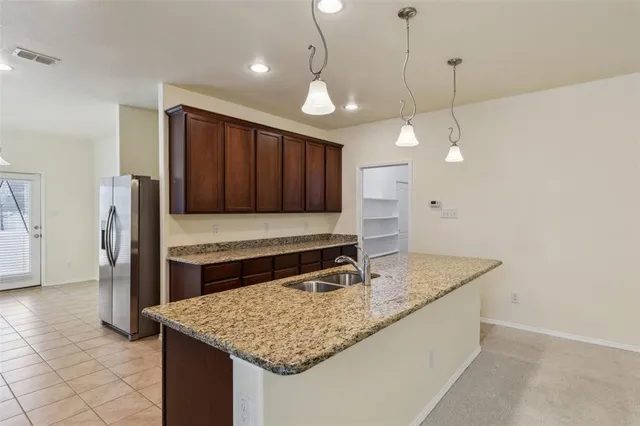 a kitchen with kitchen island a counter top stainless steel appliances and wooden cabinets