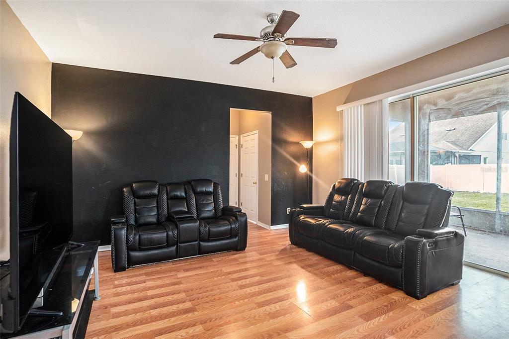 7641 Armonk Lane Wesley Chapel, FL 33545 - Photo 11 of 34 a living room with furniture ceiling fan and a flat screen tv