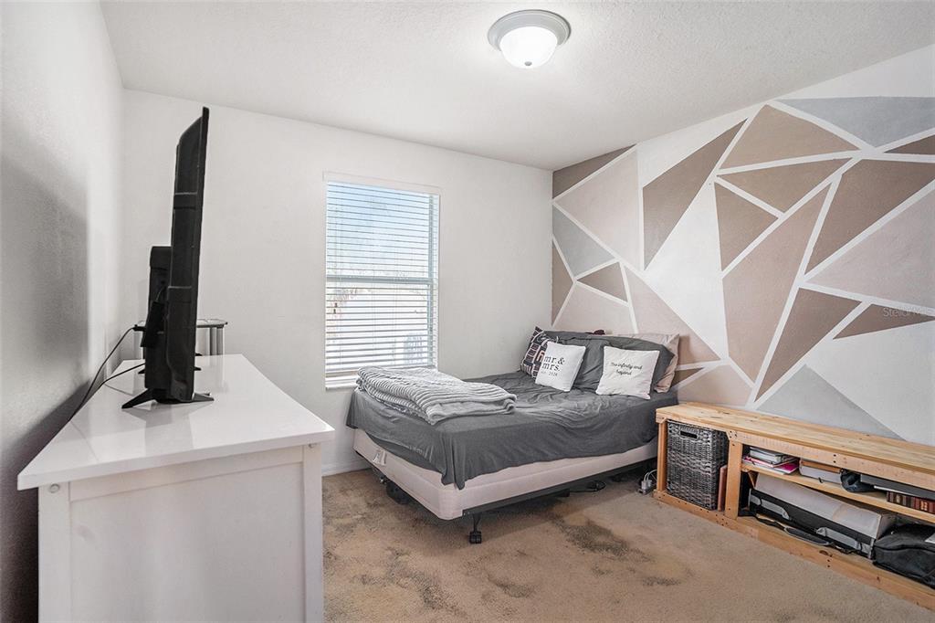 7641 Armonk Lane Wesley Chapel, FL 33545 - Photo 21 of 34 a bedroom with a bed and a flat tv screen on the dresser