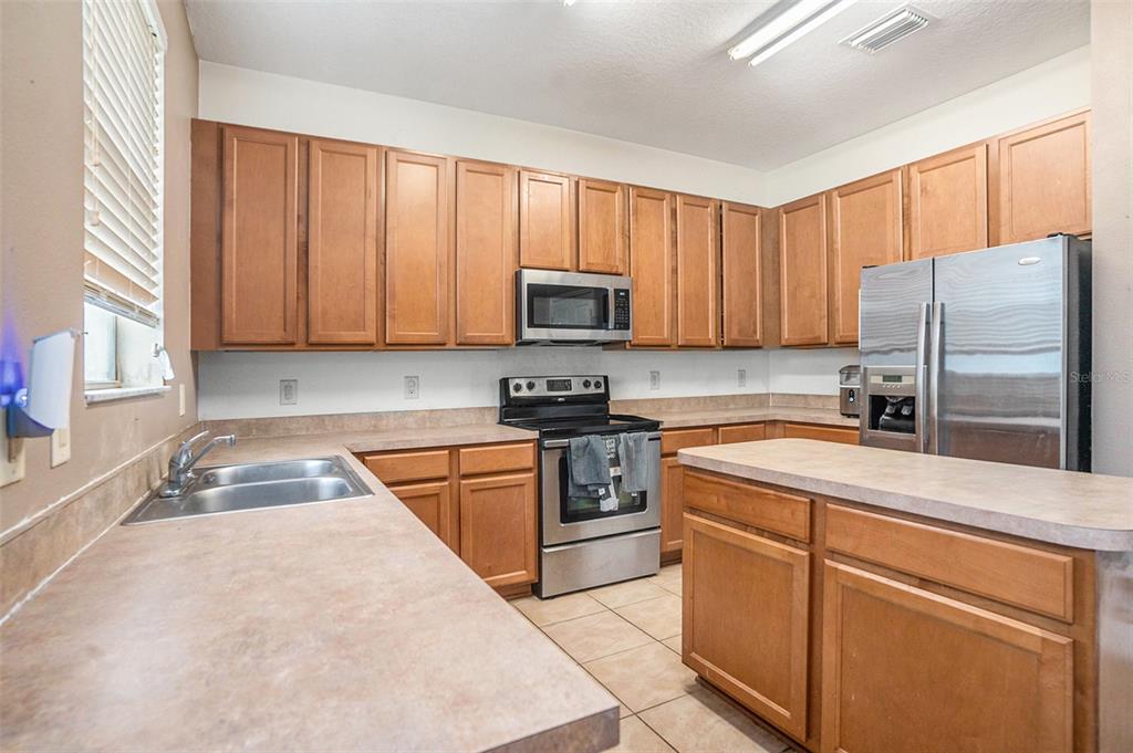 7641 Armonk Lane Wesley Chapel, FL 33545 - Photo 9 of 34 a kitchen with granite countertop a refrigerator stove top oven and sink