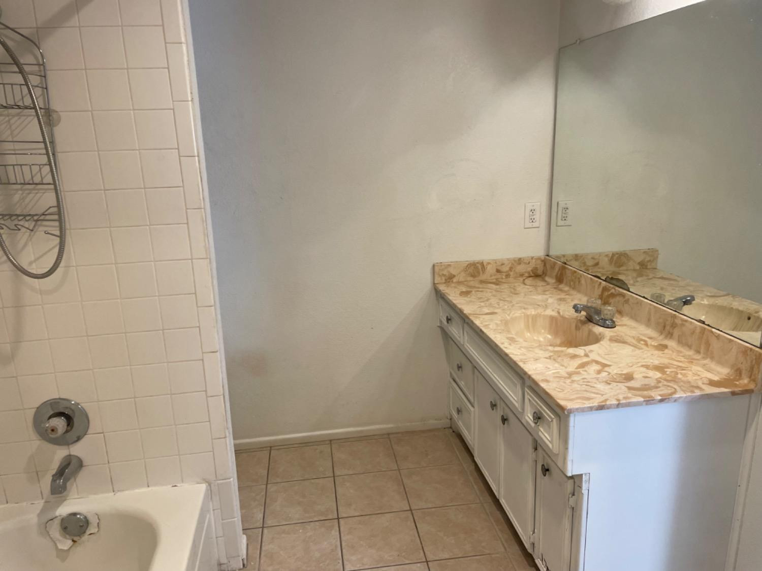 1103 80th Street, Unit A Lubbock, TX 79423 - Photo 8 of 11 a bathroom with a granite countertop sink and a mirror