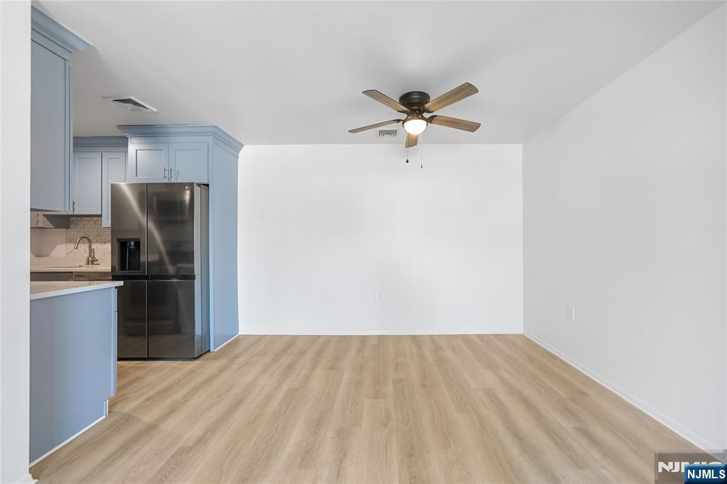 253 Park Avenue, Unit 304 Rutherford, NJ 07070 - Photo 9 of 23 a view of a kitchen with a refrigerator a ceiling fan and a wooden floor