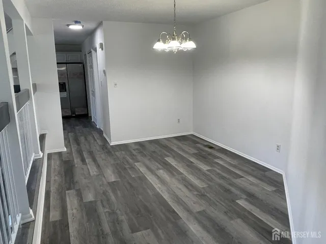 a view of a hallway with wooden floor and a chandelier