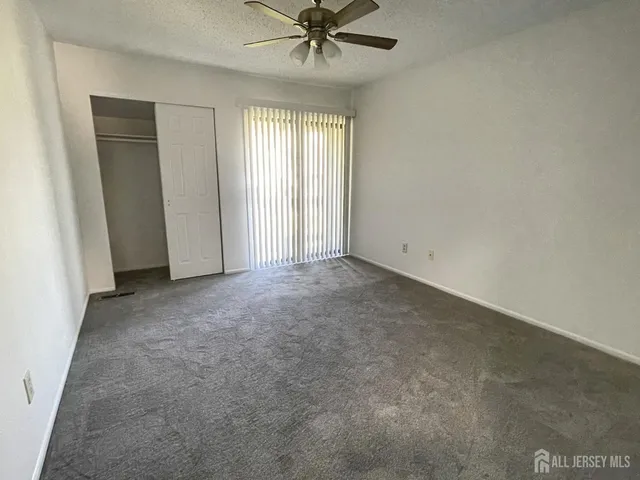 an empty room with a ceiling fan and windows