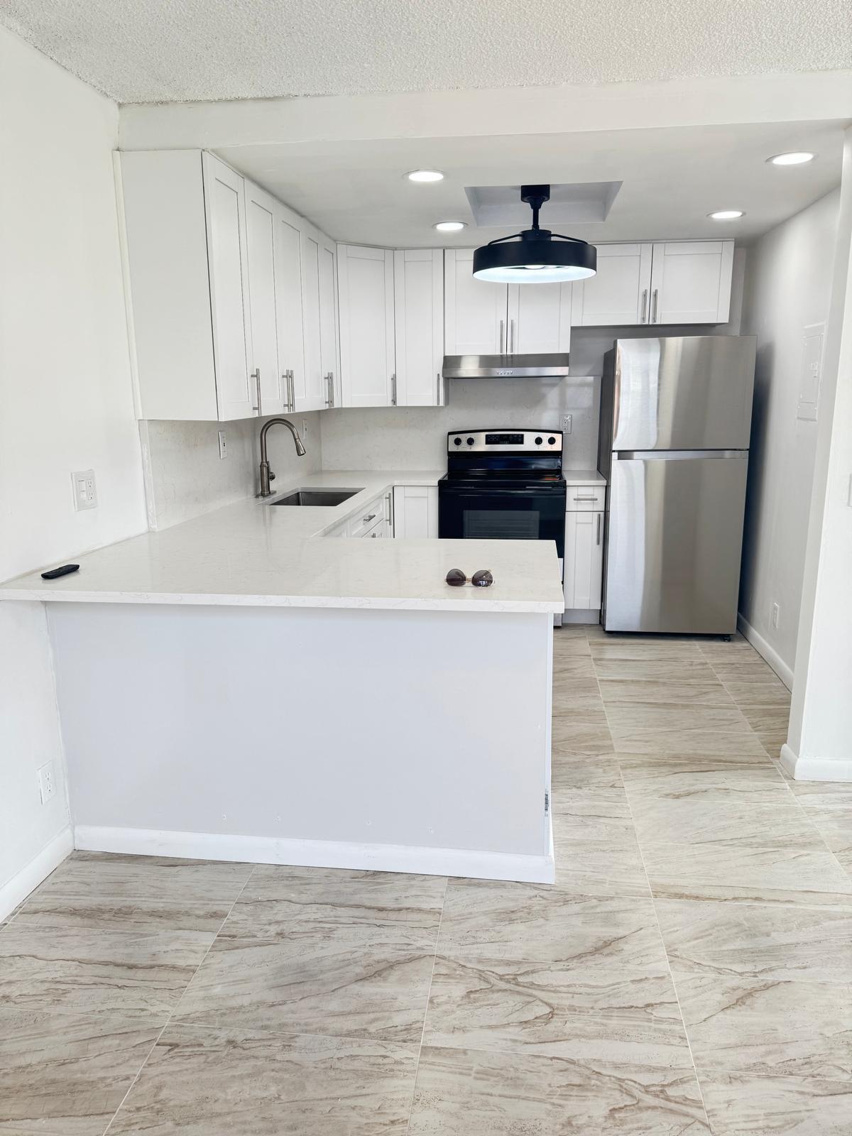 266 Burgundy Avenue, Unit 266 Delray Beach, FL 33484 - Photo 2 of 14 a kitchen with stainless steel appliances a refrigerator sink and white cabinets