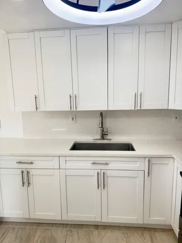 a kitchen with white cabinets and sink