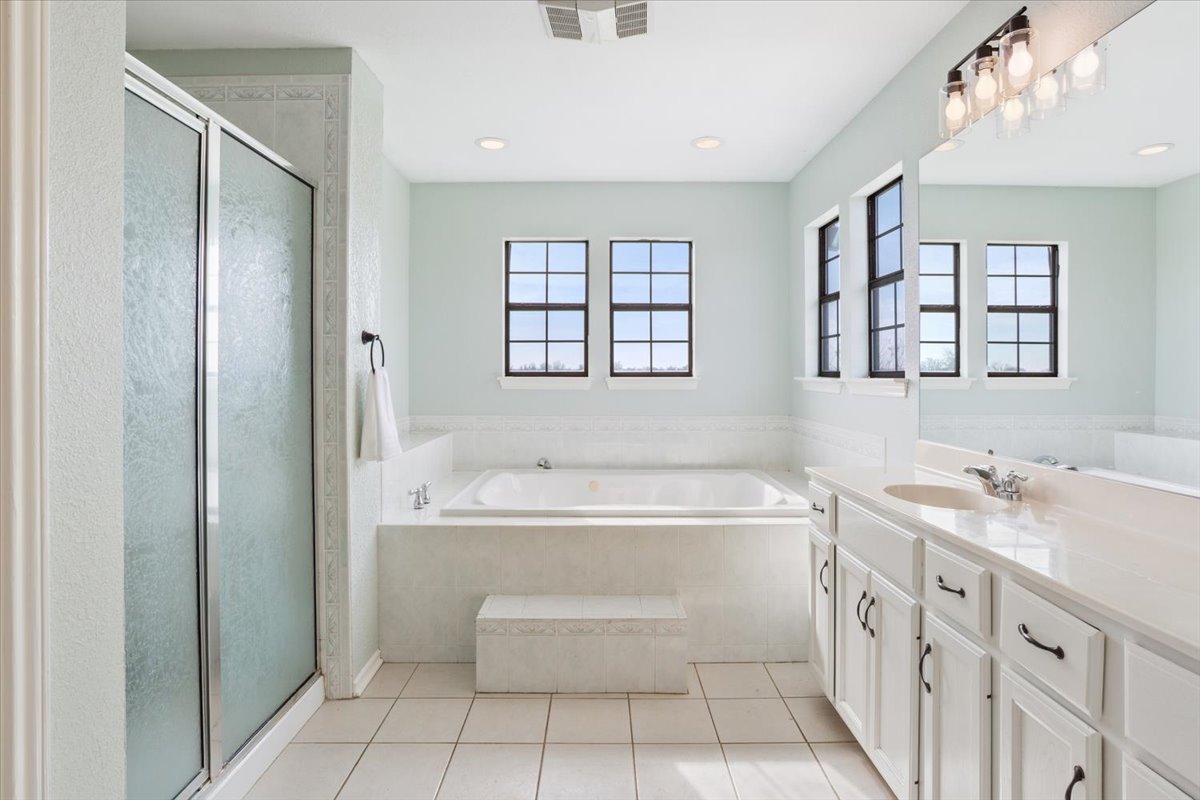 8600 Five Wells Road Rogers, TX 76569 - Photo 18 of 40 Full bathroom with a bath, vanity, a stall shower, light tile patterned floors, and healthy amount of natural light