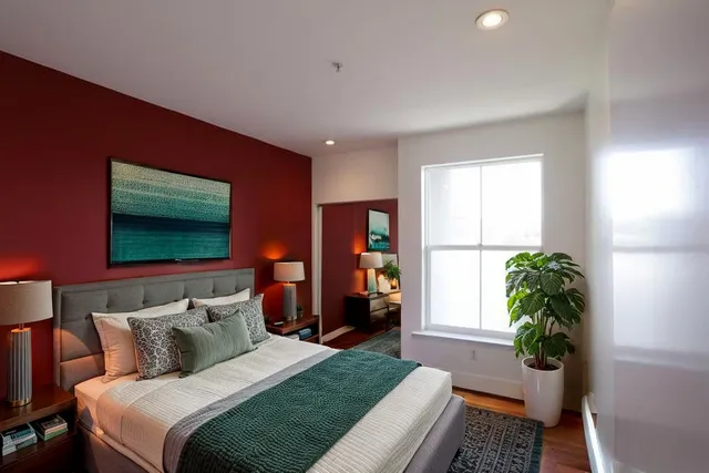 a bedroom with a bed table and a potted plant