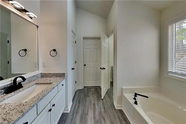 a bathroom with a granite countertop tub sink a mirror and a shower