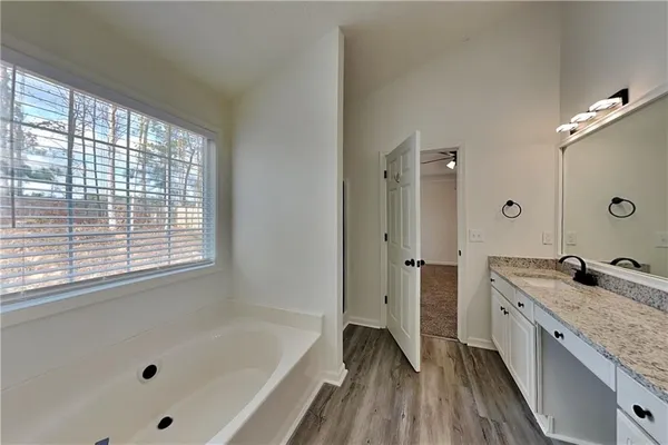 a bathroom with a granite countertop tub sink shower and mirror