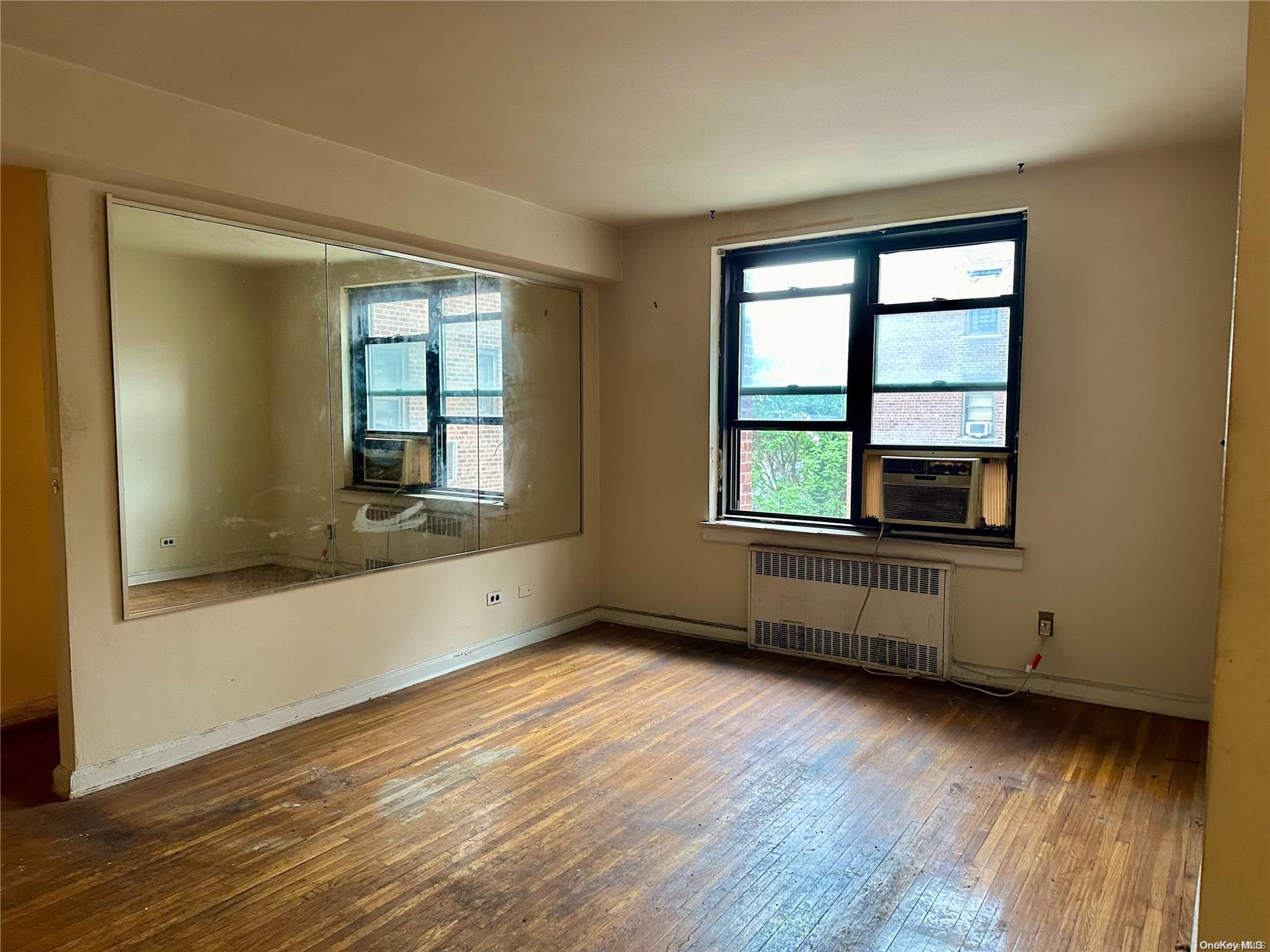 an empty room with wooden floor and windows