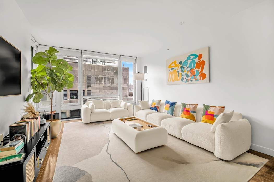 261 West 28th Street, Unit 9C Manhattan, NY 10001 - Photo 1 of 12 a living room with furniture a flat screen tv and a large window
