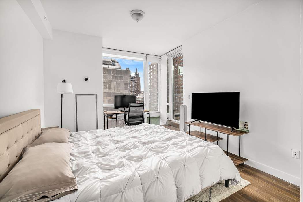 261 West 28th Street, Unit 9C Manhattan, NY 10001 - Photo 6 of 12 a bedroom with a bed and a flat screen tv