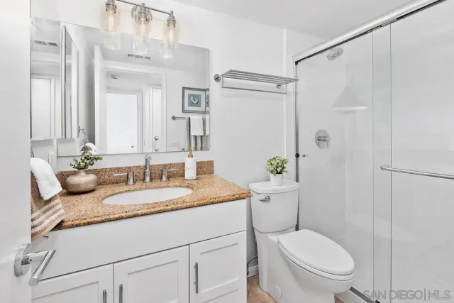 a bathroom with a granite countertop sink toilet a mirror and shower