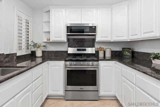 a kitchen with granite countertop white cabinets stainless steel appliances and a sink