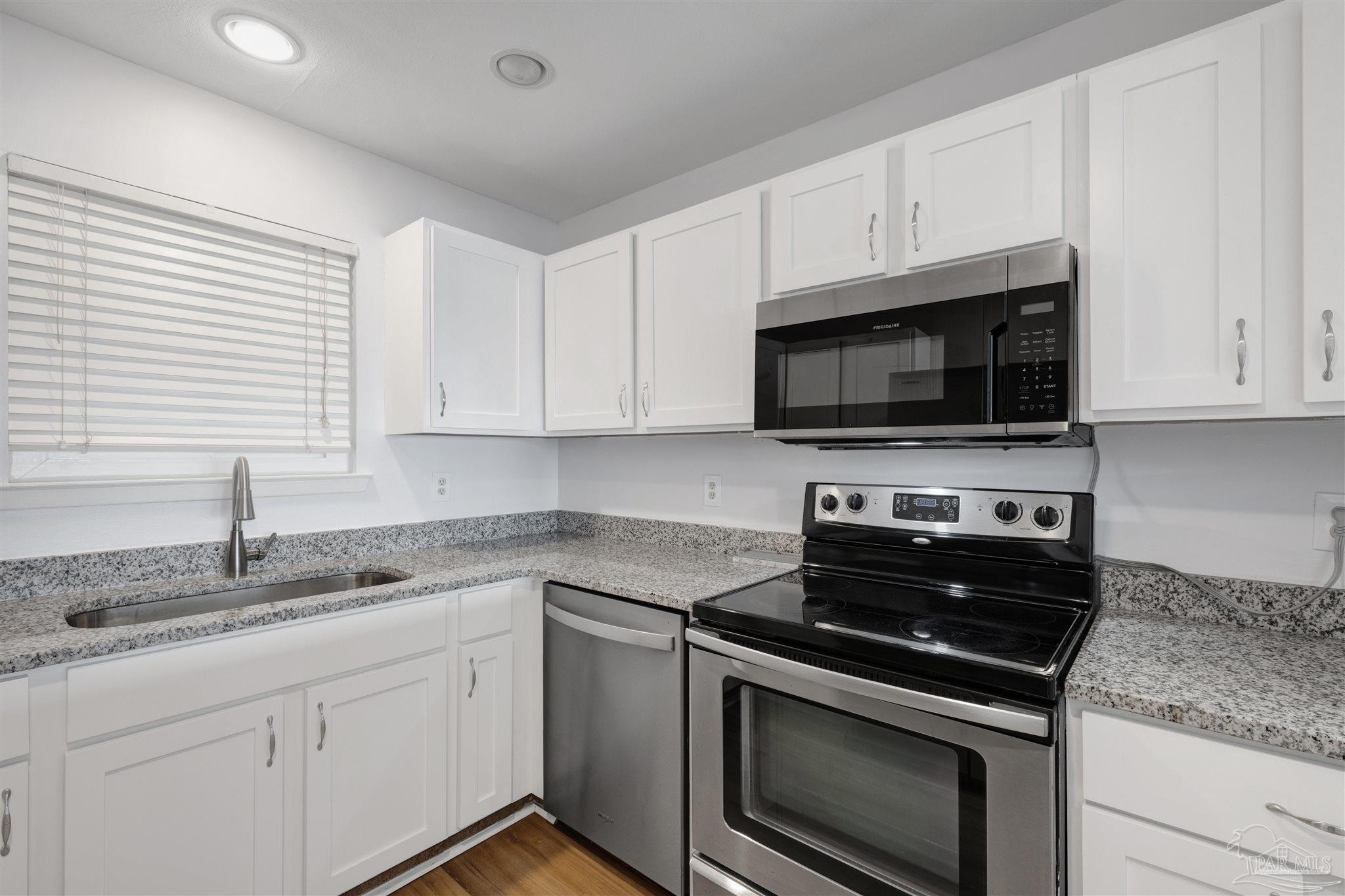 14100 River Road, Unit 334 Perdido Key, FL 32507 - Photo 17 of 35 a kitchen with granite countertop white cabinets appliances a sink and a window
