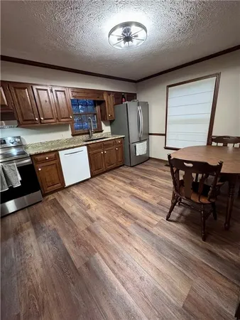 a kitchen with stainless steel appliances kitchen island granite countertop wooden cabinets and sink