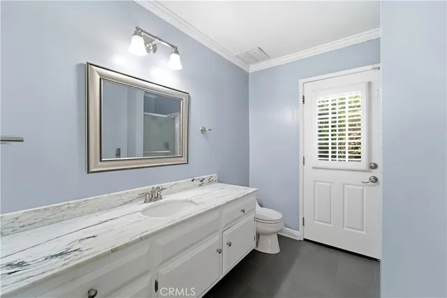a bathroom with a granite countertop sink toilet and mirror