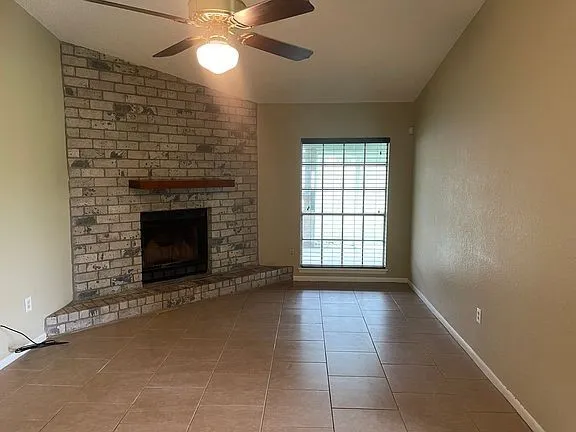 a view of an empty room with a fireplace and a window