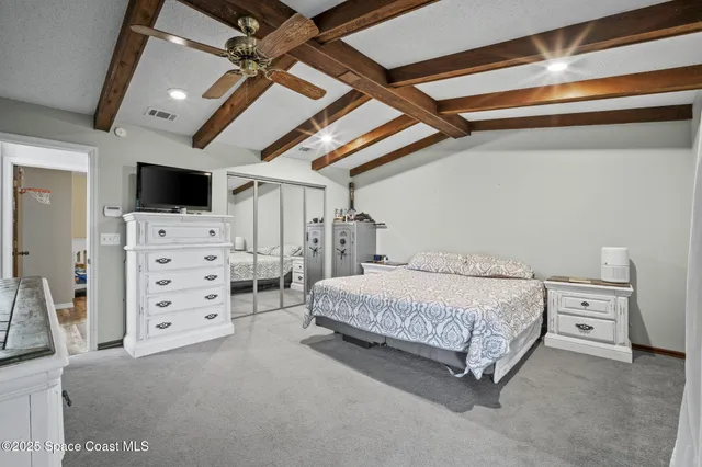 a spacious bedroom with a bed and a flat screen tv