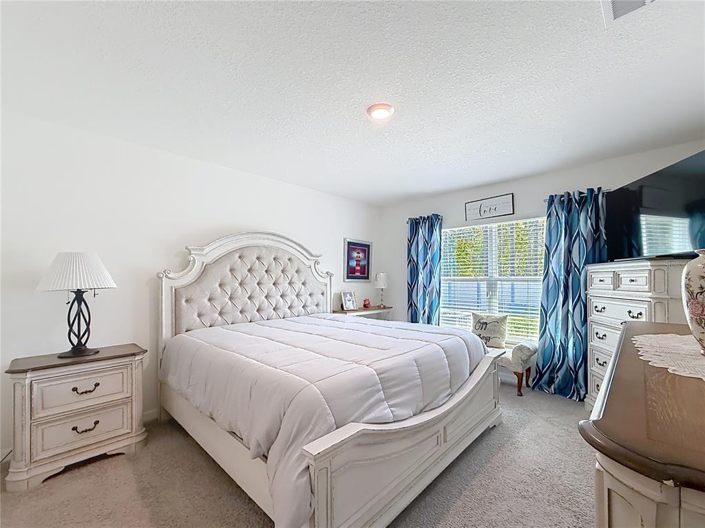 13677 Southwest 69th Terrace Ocala, FL 34473 - Photo 12 of 28 a bedroom with a bed and a flat tv screen on the dresser