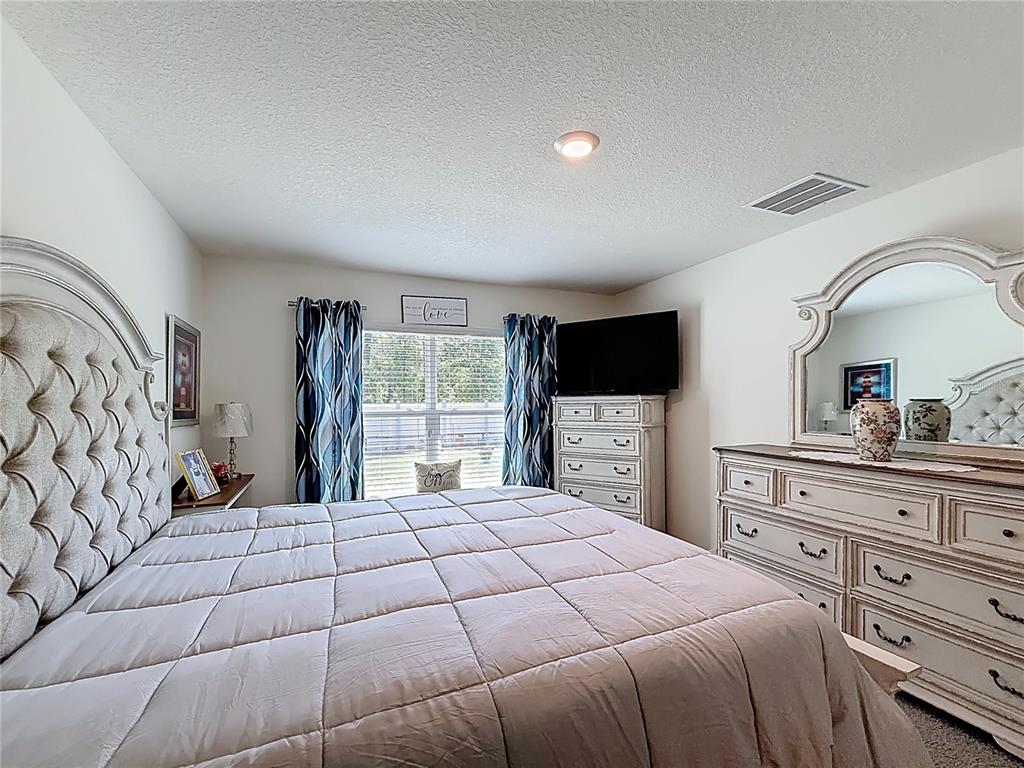 13677 Southwest 69th Terrace Ocala, FL 34473 - Photo 13 of 28 a bedroom with a large bed and a flat screen tv