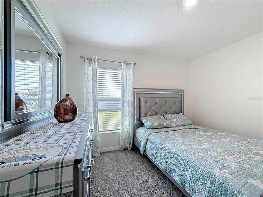 13677 Southwest 69th Terrace Ocala, FL 34473 - Photo 17 of 28 a bedroom with a bed and large windows