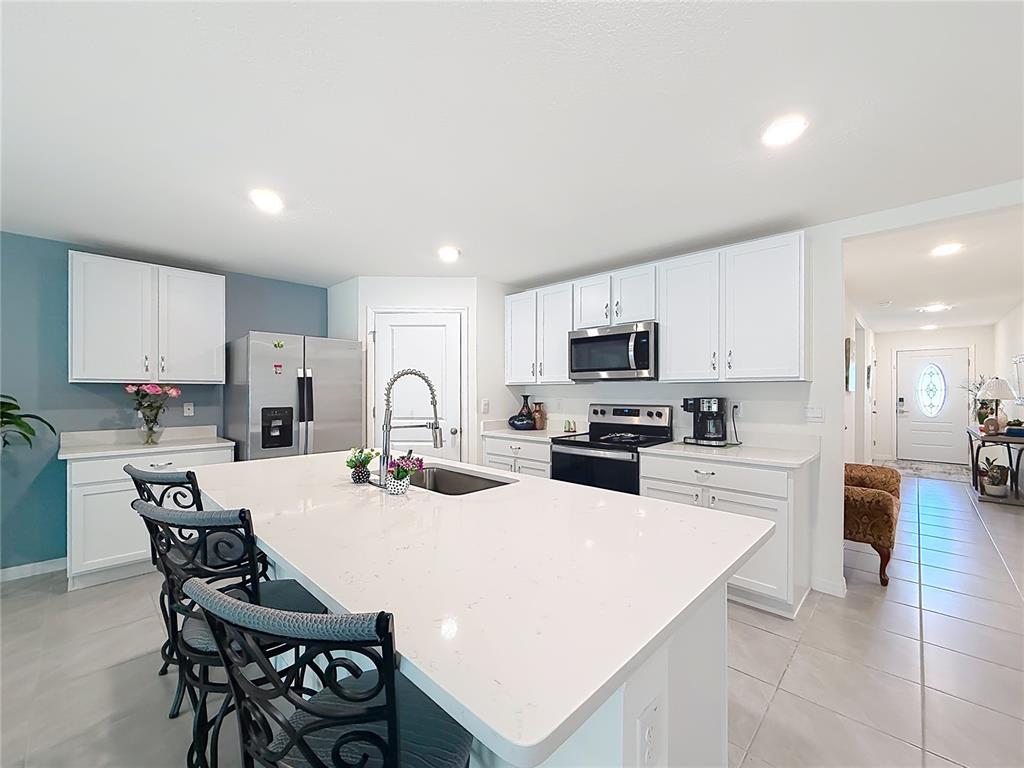 13677 Southwest 69th Terrace Ocala, FL 34473 - Photo 4 of 28 a kitchen with stainless steel appliances kitchen island granite countertop a stove a sink a refrigerator and white cabinets with wooden floor