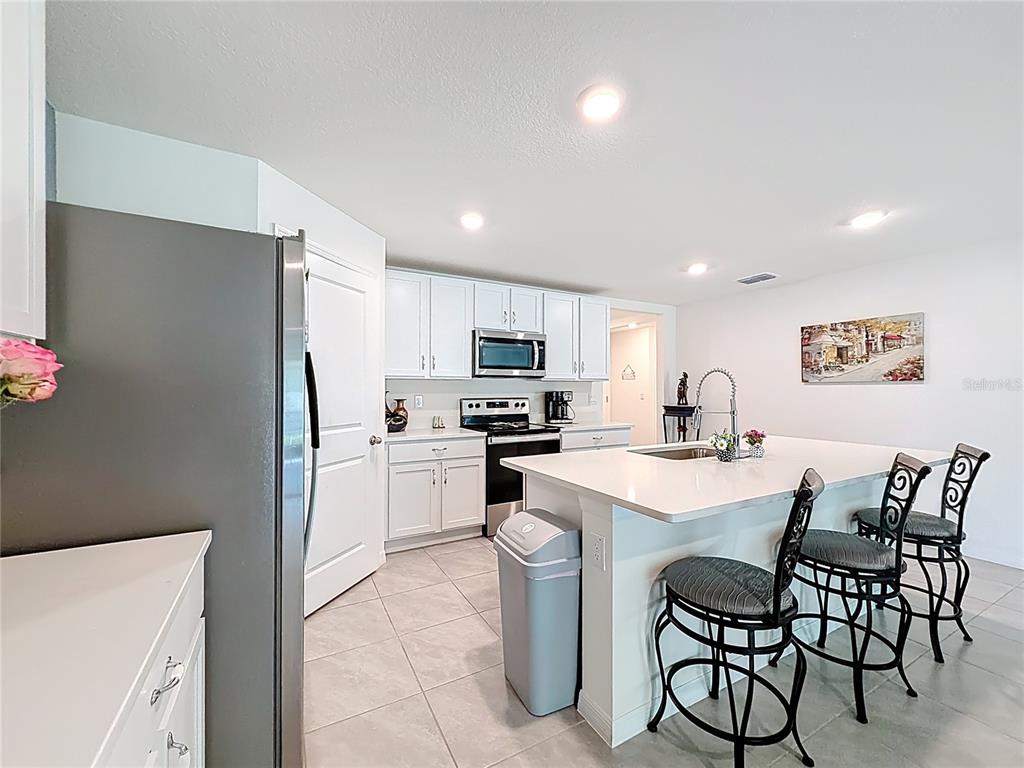 13677 Southwest 69th Terrace Ocala, FL 34473 - Photo 6 of 28 a kitchen with a refrigerator a stove microwave oven with white cabinets and wooden floor