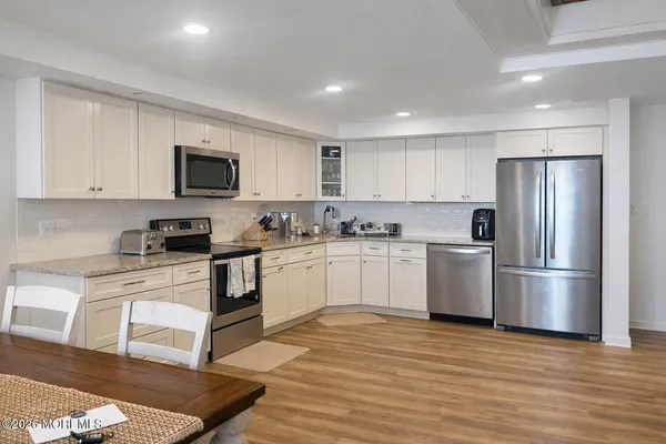 a kitchen with stainless steel appliances a white stove top oven a sink dishwasher and white cabinets with wooden floor