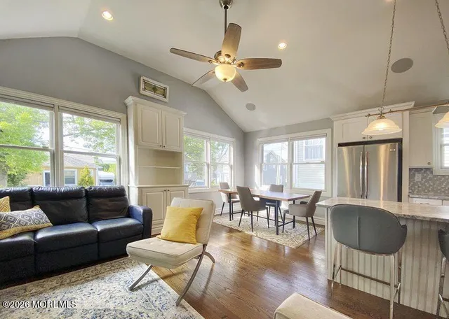 a living room with furniture two window and a dining table
