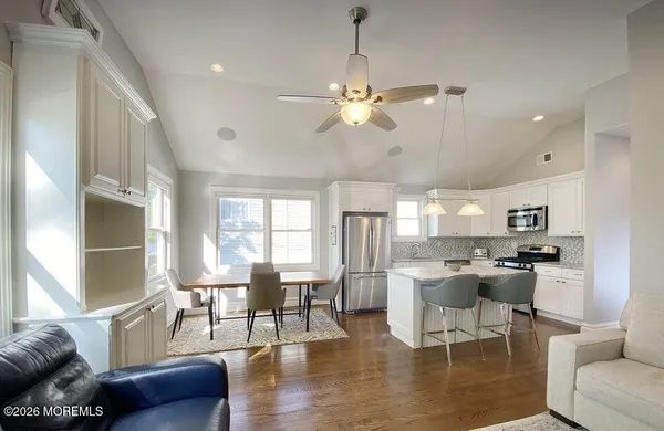 a living room with furniture kitchen view and a chandelier