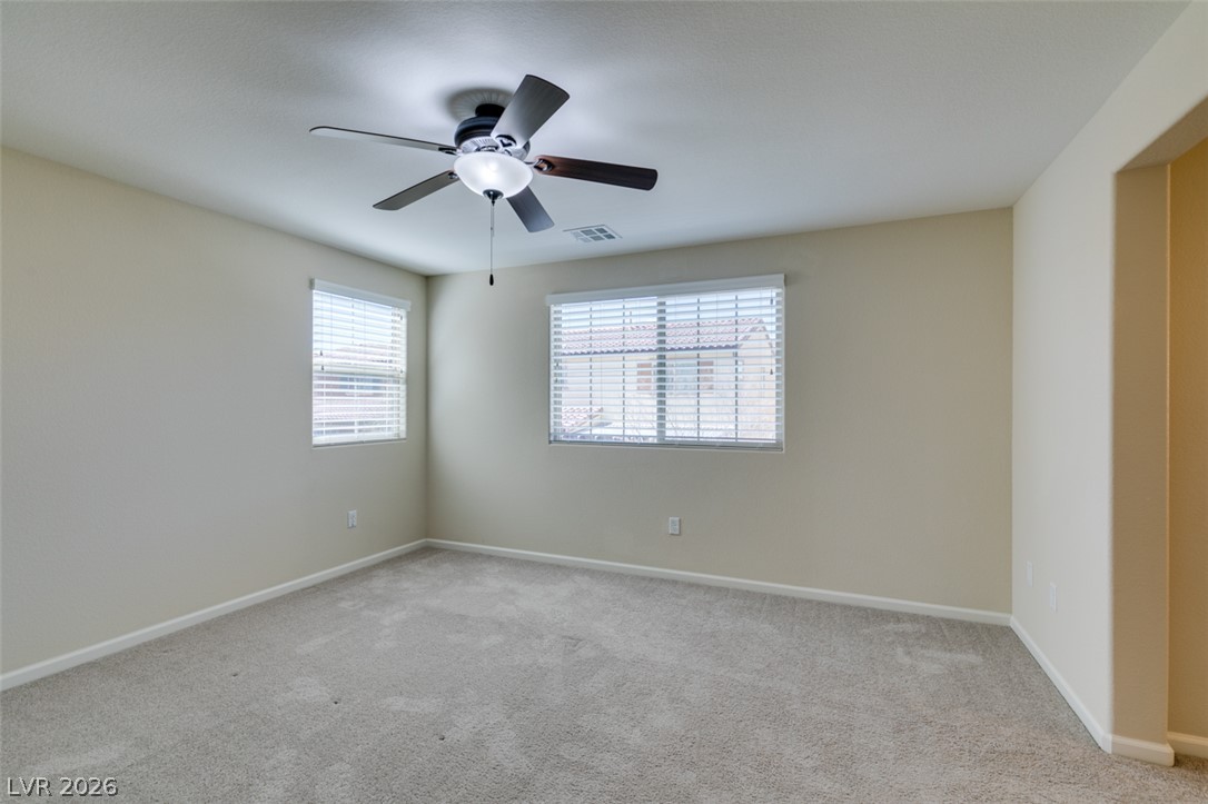 2549 Sable Ridge Street Henderson, NV 89044 - Photo 40 of 48 An airy bedroom with plush carpeting features ample natural light through multiple windows and a ceiling fan for comfort.
