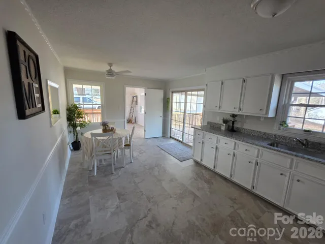 a large white kitchen with sink and dining table