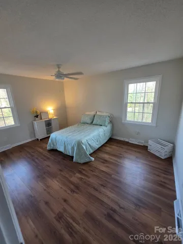 a bedroom with wooden floor and window