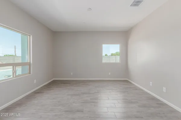 a view of an empty room with window and wooden floor