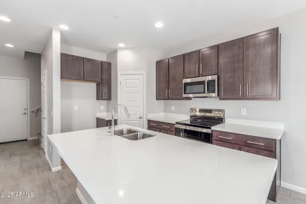 a kitchen with granite countertop a stove top oven a sink dishwasher a refrigerator and a microwave oven with wooden floor