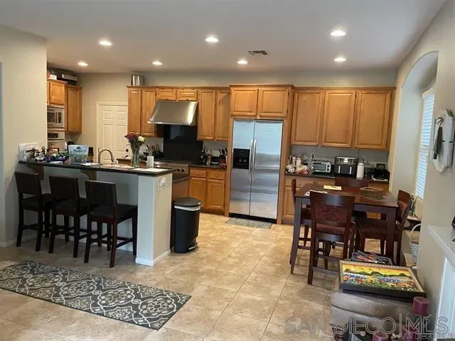 a kitchen with kitchen island granite countertop a stove a sink a dining table and chairs