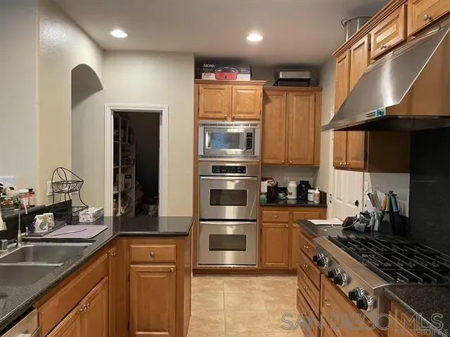 a kitchen with stainless steel appliances granite countertop a sink a stove and a refrigerator