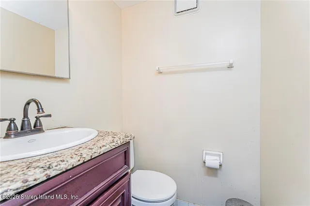 a bathroom with a granite countertop sink and a toilet