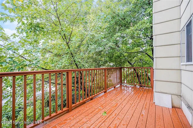 a balcony with wooden floor and trees in the back