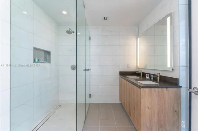 a bathroom with a granite countertop sink a mirror and shower