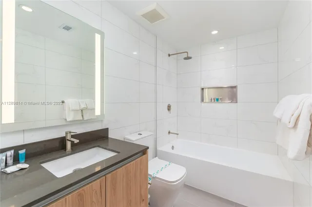 a bathroom with a granite countertop sink toilet mirror and bathtub