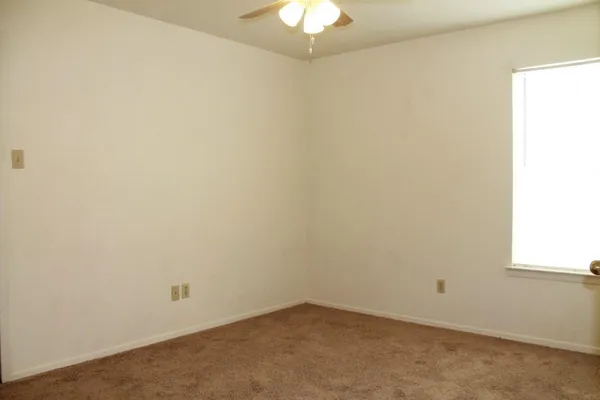 an empty room with a chandelier fan and closet
