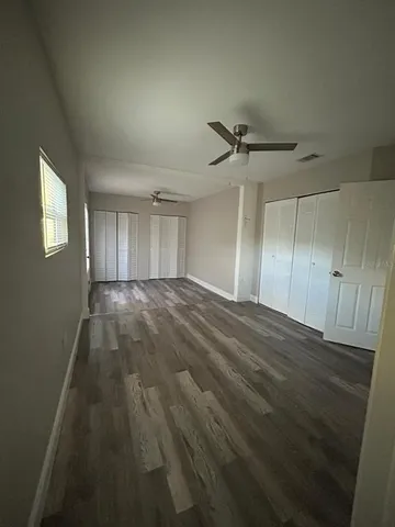an empty room with wooden floor and fan