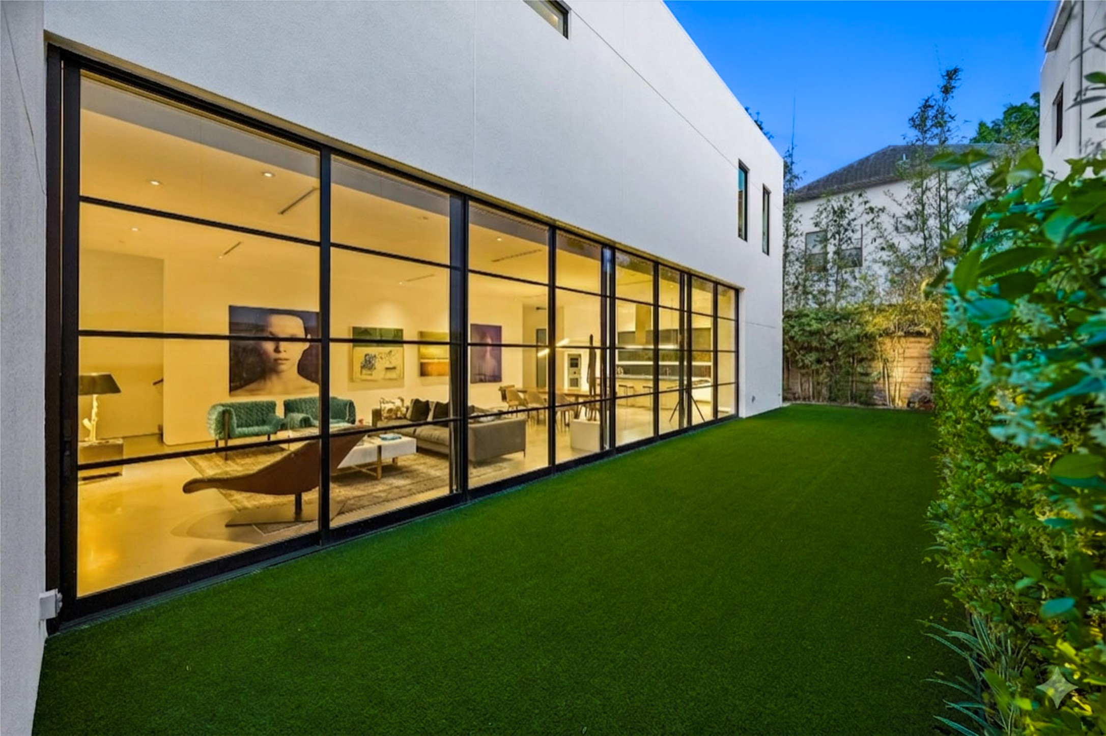 1527 Indiana Street Houston, TX 77006 - Photo 3 of 30 Serene outdoor retreat showcasing artificial turf and privacy-enhancing landscaping, while an expansive wall of floor-to-ceiling steel-framed windows creates a striking connection between the indoors and outdoors.